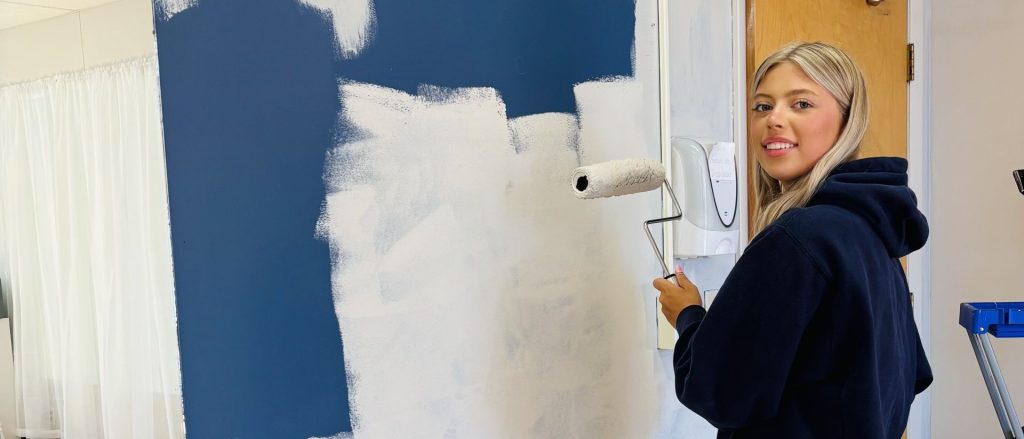 woman painting wall and smiling