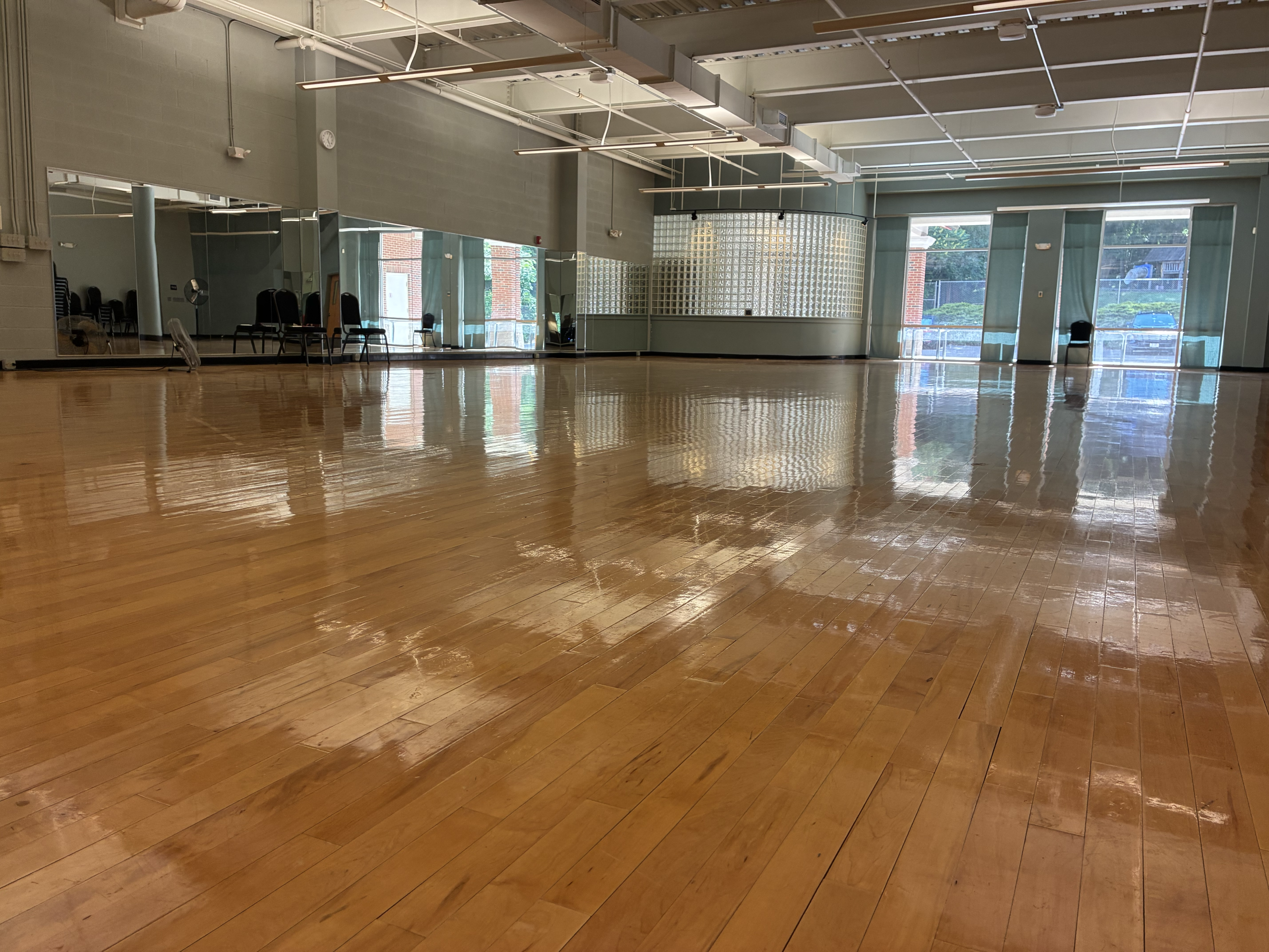 large room with hardwood floors, mirrors, and large windows