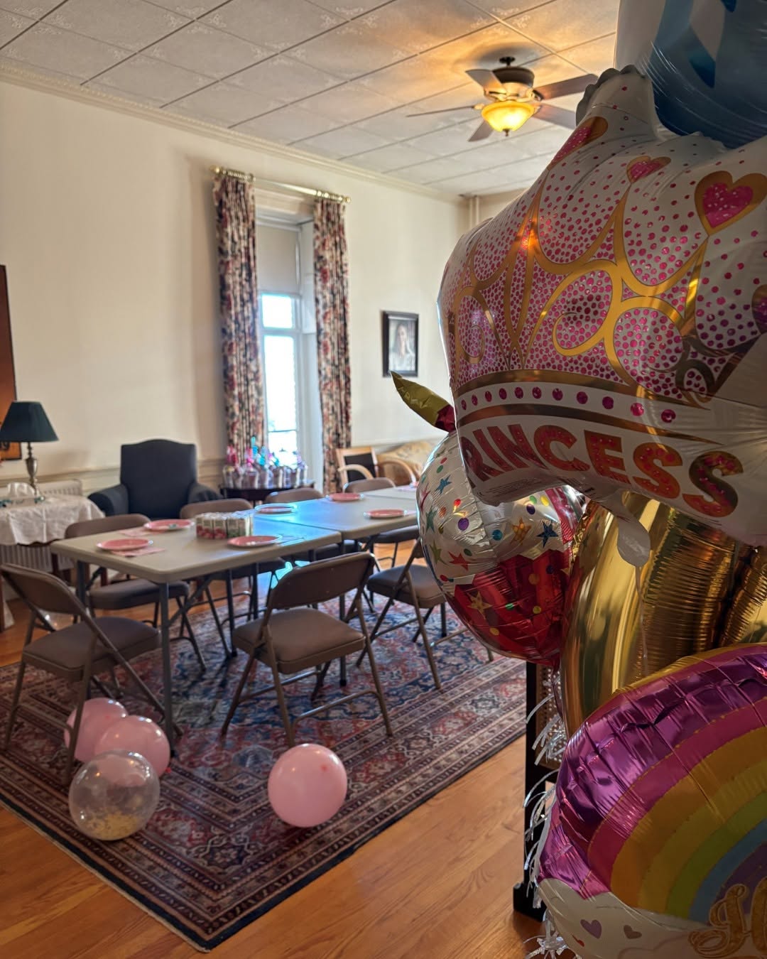 mid-sized room with vintage furniture, set up with folding tables, chairs, and party decorations