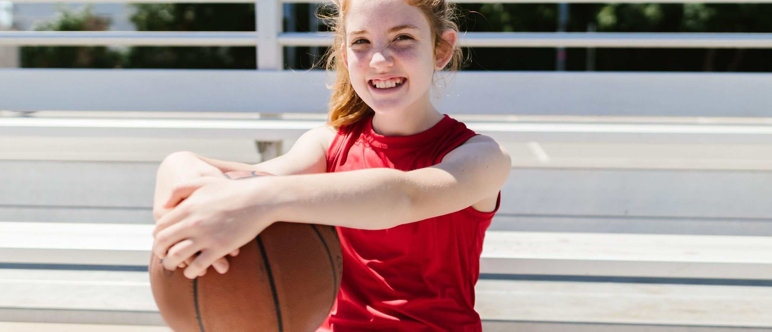 girl holding basketball and smiling