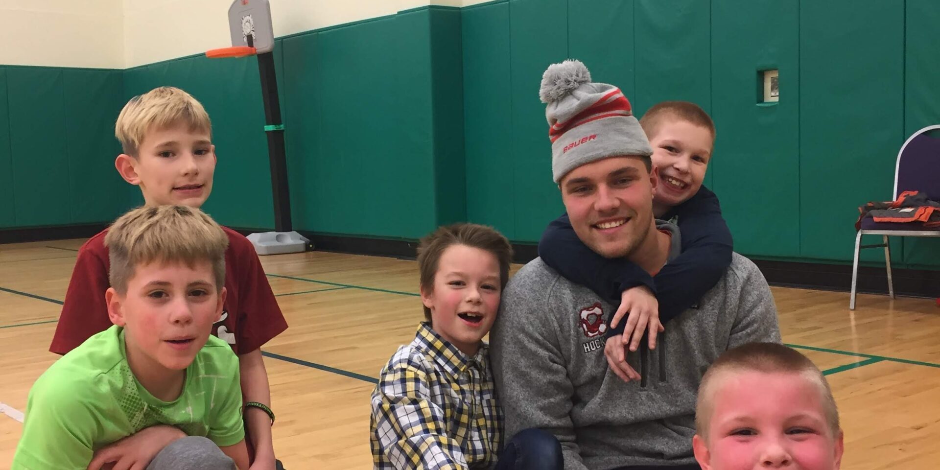 man and group of kids sitting together and smiling
